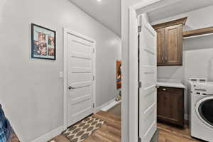 Laundry room featuring washer / dryer, baseboards, cabinet space, and light wood finished floors