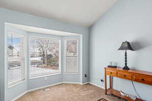 Interior space featuring carpet, visible vents, vaulted ceiling, and baseboards