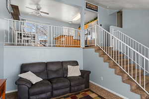 Living area featuring carpet flooring, a ceiling fan, and baseboards