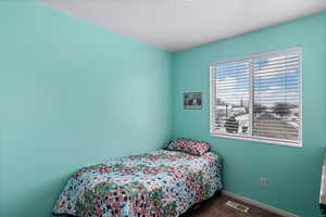 Bedroom featuring dark colored carpet, visible vents, and baseboards