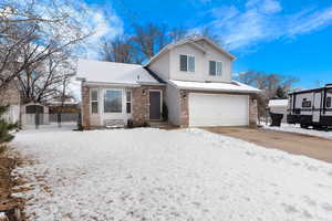 View of front of property with a garage, brick siding, fence, and driveway