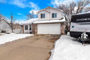 View of front of house with concrete driveway, brick siding, an attached garage, and central air condition unit