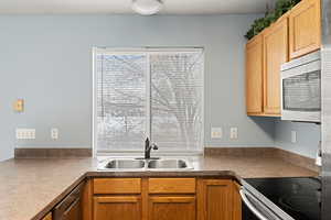 Kitchen featuring appliances with stainless steel finishes, light countertops, and a sink