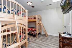 Third bedroom featuring twin bunkbeds, dresser and TV and wood finished floors