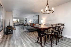 Dining room with modern wood and iron table, chairs,  a chandelier, and wood finished floors