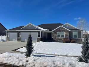 Craftsman house with a garage, stone siding, and driveway