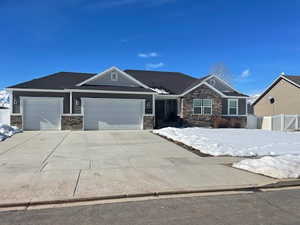 Craftsman house with a garage, stone siding, fence, and concrete driveway