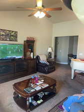 Living room with lofted ceiling, carpet flooring, a ceiling fan, and baseboards