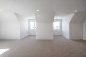 Bonus room with light colored carpet, recessed lighting, plenty of natural light, and a textured ceiling