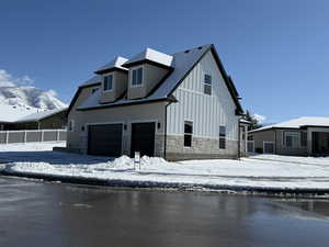 Exterior space with a garage, stone siding, and board and batten siding