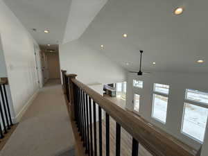 Hallway featuring recessed lighting, visible vents, baseboards, vaulted ceiling, and an upstairs landing