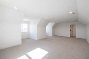 Bonus room with lofted ceiling, light colored carpet, and recessed lighting
