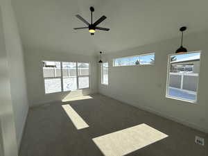 Spare room featuring baseboards, vaulted ceiling, visible vents, and dark colored carpet