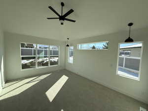 Carpeted spare room featuring vaulted ceiling, ceiling fan, and baseboards