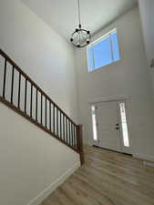 Foyer entrance featuring a chandelier, visible vents, baseboards, stairs, and light wood finished floors