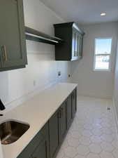 Kitchen featuring a textured ceiling, light countertops, a sink, and baseboards