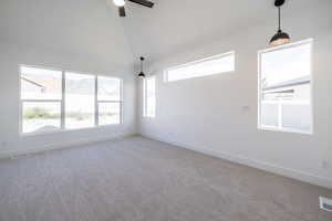 Empty room featuring carpet floors, a ceiling fan, and high vaulted ceiling