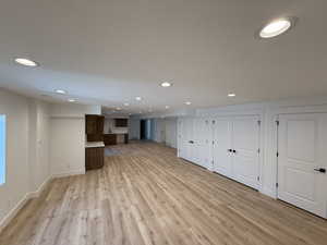 Unfurnished living room with light wood-style floors, recessed lighting, and baseboards