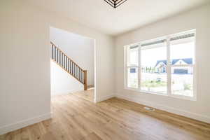 Unfurnished room with light wood finished floors and stairway
