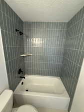 Full bathroom featuring tub / shower combination, a textured ceiling, and toilet