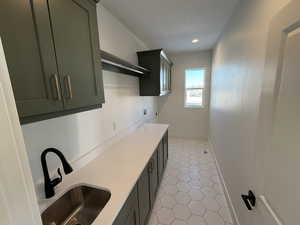 Interior space with cabinet space, baseboards, a sink, a textured ceiling, and electric dryer hookup