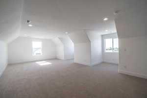 Additional living space featuring vaulted ceiling, light carpet, a textured ceiling, and recessed lighting