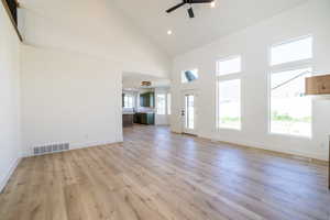 Unfurnished living room featuring high vaulted ceiling, a ceiling fan, light wood-style floors, and recessed lighting