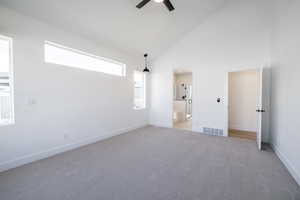 Empty room with a ceiling fan, light colored carpet, and high vaulted ceiling
