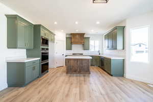 Kitchen with appliances with stainless steel finishes, green cabinetry, light wood-style flooring, a center island, and recessed lighting