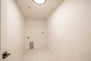 Laundry room with electric dryer hookup, hookup for a washing machine, and light tile patterned floors