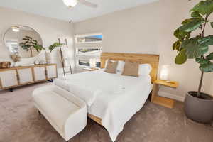 Bedroom with baseboards, dark carpet, and a ceiling fan