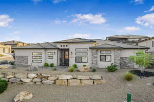 View of front of property featuring stone siding, a tiled roof, and stucco siding