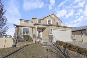 Traditional-style house with driveway, a garage, a gate, fence, and stucco siding