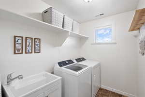 Laundry room with baseboards, visible vents, a sink, and washing machine and clothes dryer