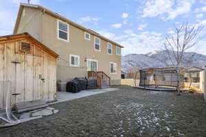 Back of property featuring a fenced backyard, a trampoline, a mountain view, and stucco siding