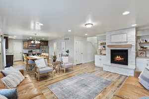 Living room with recessed lighting, light wood-style flooring, baseboards, and an inviting chandelier