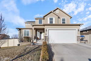 Traditional home featuring stucco siding, driveway, an attached garage, and fence