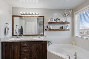 Bathroom featuring double vanity, a garden tub, and a sink