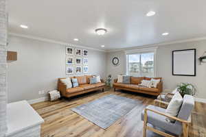 Living area with crown molding, baseboards, and wood finished floors