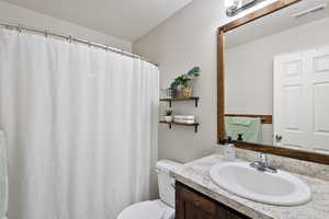 Bathroom with toilet, a textured ceiling, vanity, and visible vents