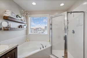 Bathroom with a stall shower, vanity, a bath, and recessed lighting