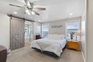 Bedroom featuring a barn door, recessed lighting, visible vents, and light colored carpet