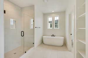 Bathroom with a soaking tub, a shower stall, toilet, and baseboards