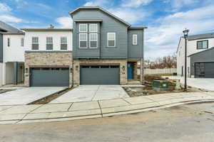 View of property with a garage, driveway, and stone siding