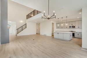 Kitchen featuring appliances with stainless steel finishes, open floor plan, a center island, gray cabinets, and light countertops