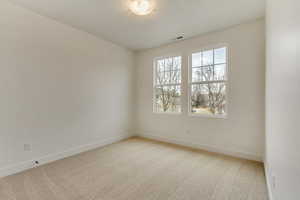 Empty room with light carpet, visible vents, and baseboards