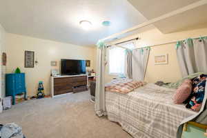 Bedroom with light carpet, a textured ceiling, and baseboards