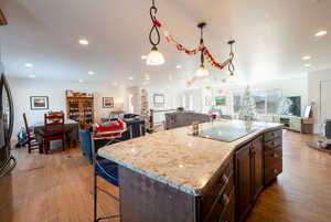 Kitchen featuring open floor plan, hanging light fixtures, light wood-style flooring, and black electric stovetop