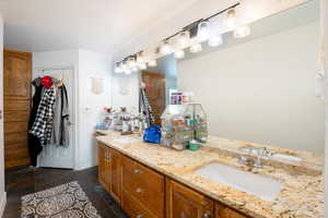 Bathroom with double vanity, stone tile flooring, and a sink