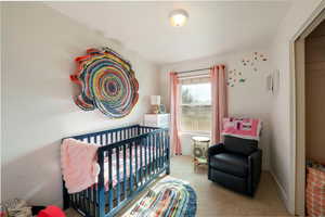 Bedroom featuring carpet floors, baseboards, and a crib